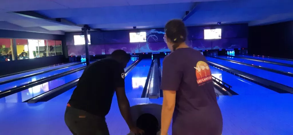 Deux personnes jouant au bowling dans une piste de bowling.