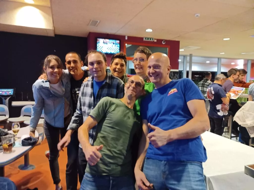 Un groupe de personnes posant pour une photo dans une piste de bowling.