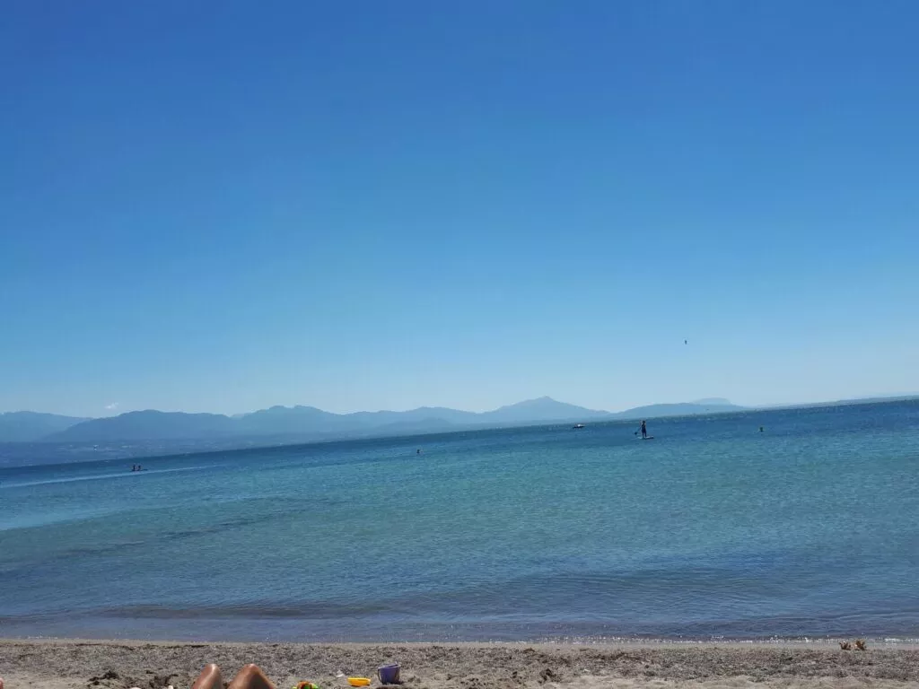 Un groupe de personnes assises sur la plage avec un bateau en arrière-plan.