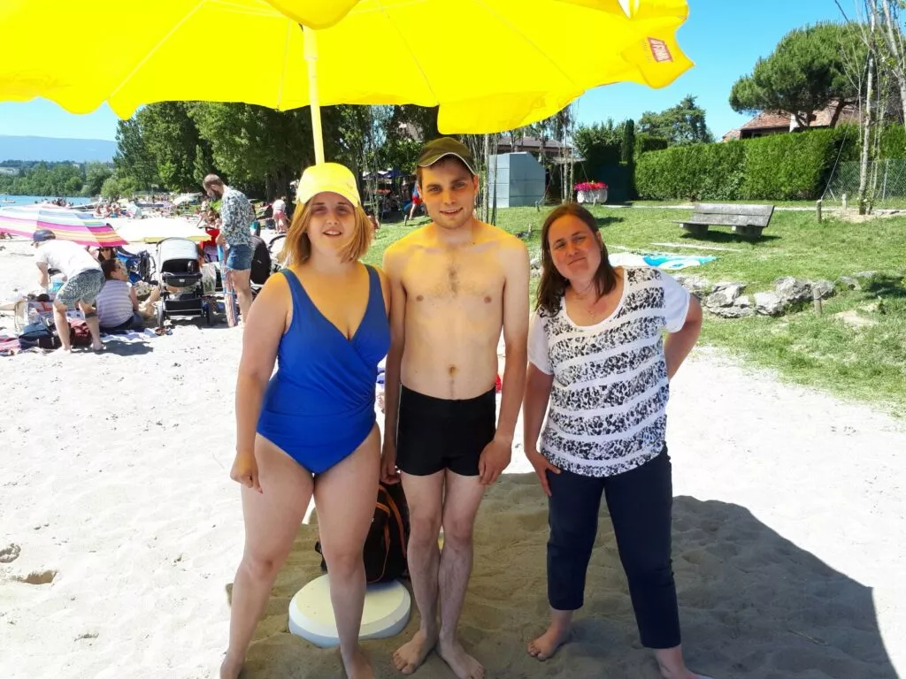 Trois personnes posant sous un parapluie jaune.
