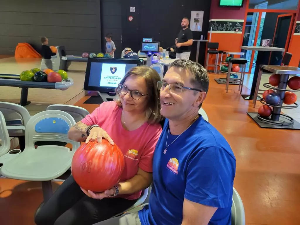 Un homme et une femme tenant une boule de bowling dans une piste de bowling.