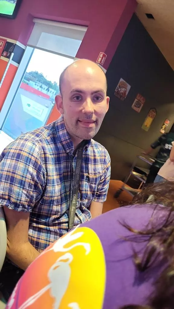Un homme vêtu d’une chemise violette est assis dans un restaurant.
