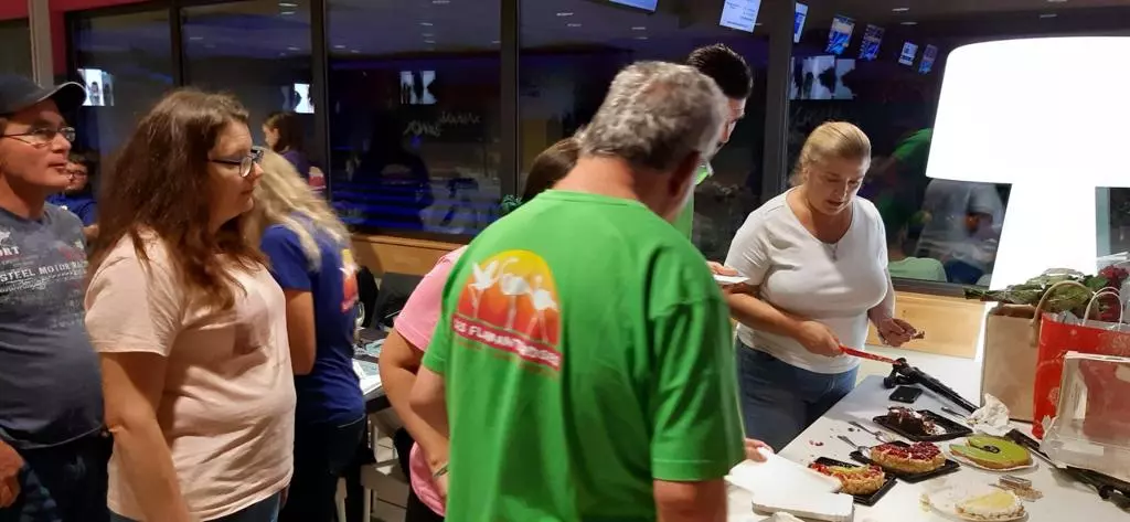 Un groupe de personnes debout autour d’une table avec de la nourriture.