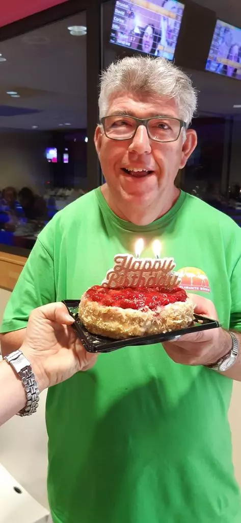 Un homme en chemise verte tenant un gâteau.