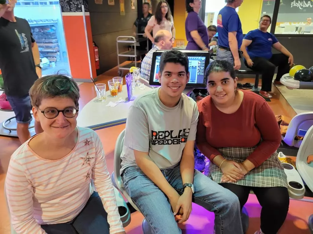 Trois personnes posant pour une photo dans un bowling.