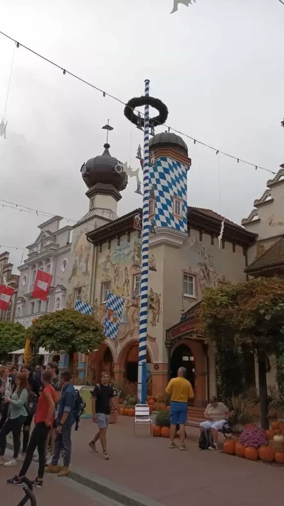 Un groupe de personnes marche dans une rue d’un parc d’attractions.