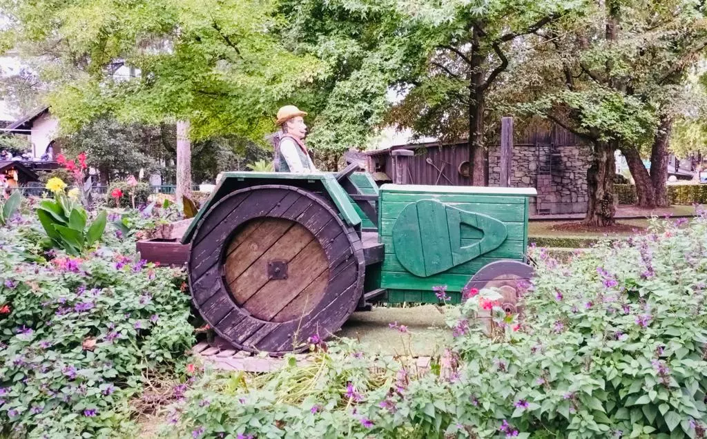 Un homme conduisant un tracteur dans un jardin.