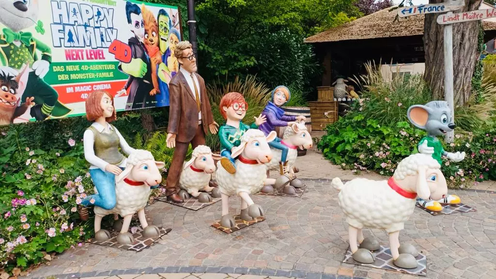 Un groupe de statues de personnes et d'animaux devant un panneau.