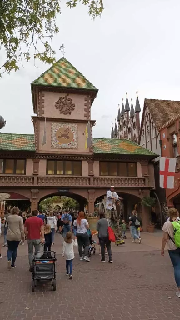 Un groupe de personnes marchant dans une rue avec une tour d’horloge.