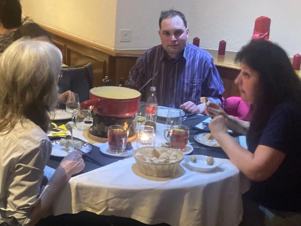Trois personnes dînant à une table de restaurant dotée d'un caquelon à fondue.