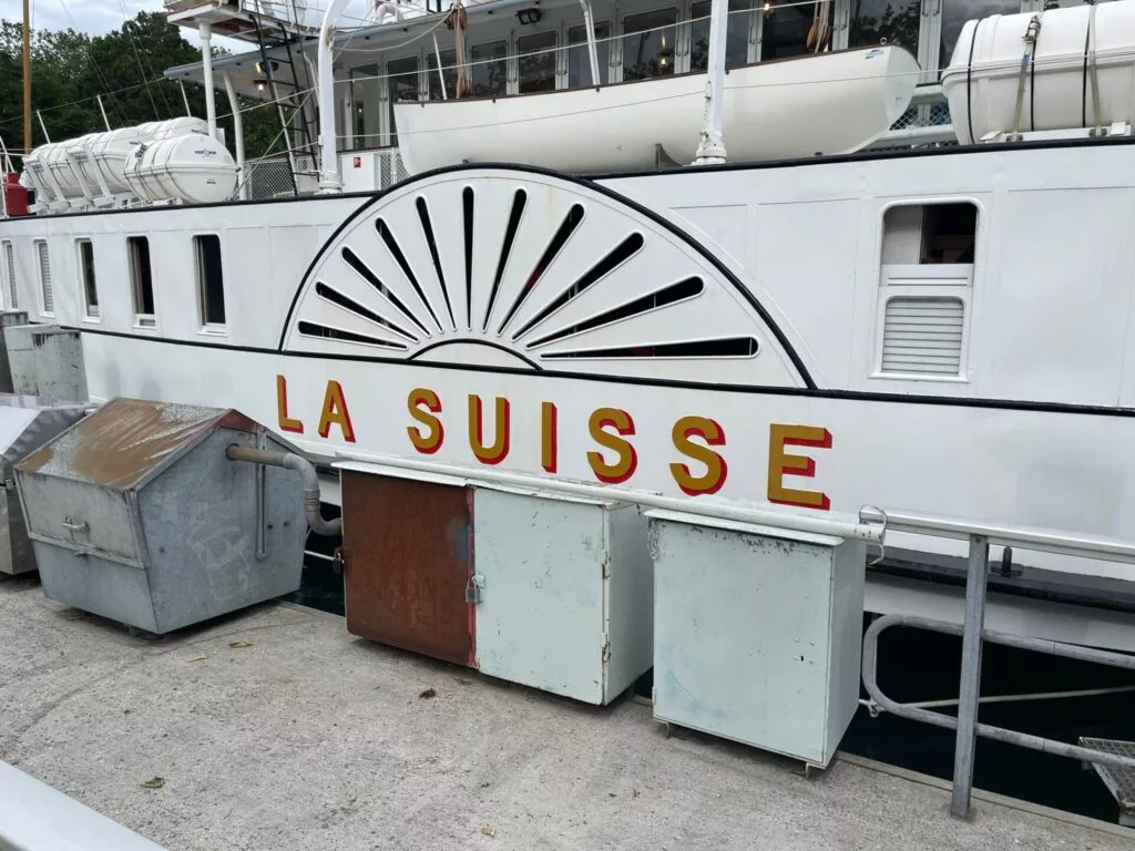 Vue latérale d'un bateau blanc nommé « La Suisse » amarré à un quai.