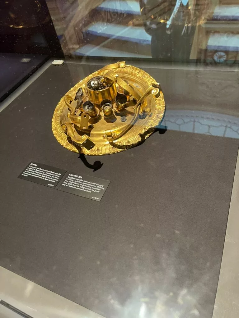 Un artefact mécanique doré aux détails complexes affichés sur une surface noire, accompagné de panneaux d'information.