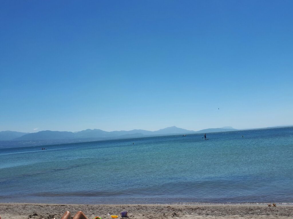 Un groupe de personnes assises sur la plage avec un bateau en arrière-plan.