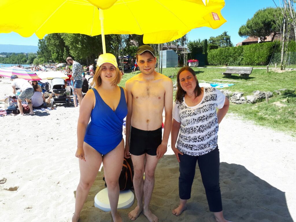 Trois personnes posant sous un parapluie jaune.