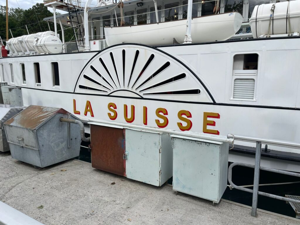 Vue latérale d'un bateau blanc nommé « La Suisse » amarré à un quai.